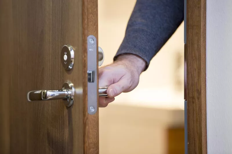 A person opening a wooden door
