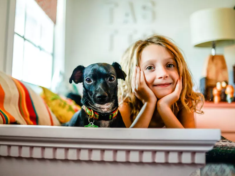 girl sitting with dog on the bed
