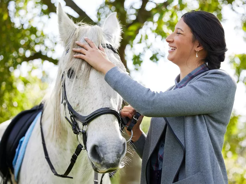 Shot of an attractive young woman standing with her horse in a forest