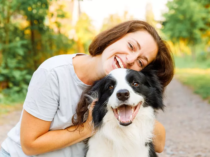 Smiling woman playing with cute puppy dog