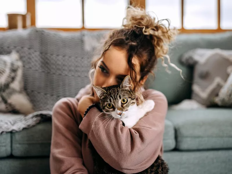 Young woman bonding with her cat in apartment