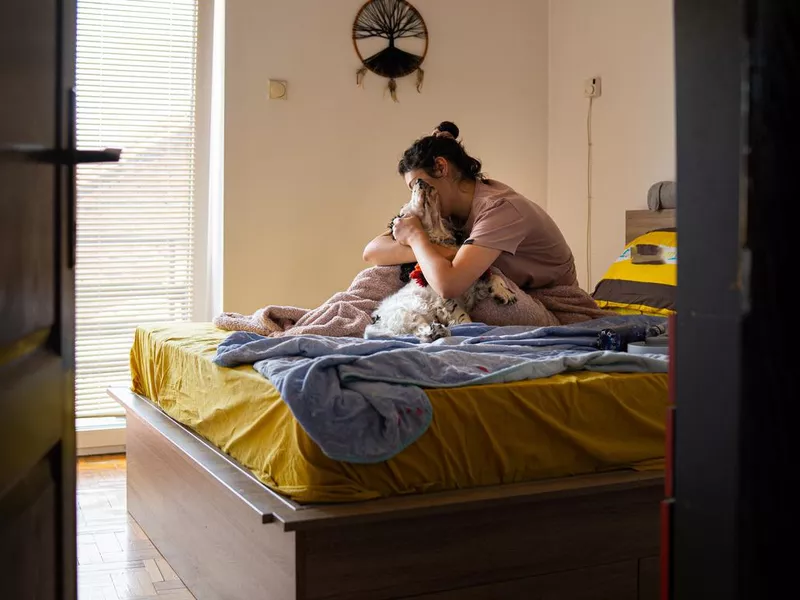 Woman sitting on a bed hugging her dog affectionately